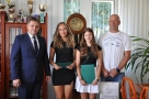 dziewczęta trzymają teczki z gratulacjami, obok stoi trener z torbą upominkową oraz burmistrz
