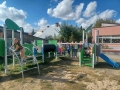 dzieci znajdują się w ogrodzie przedszkolnym, bawią się na nowych urządzeniach terenowych.