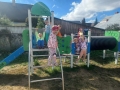 dzieci znajdują się w ogrodzie przedszkolnym, bawią się na nowych urządzeniach terenowych.