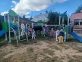 dzieci znajdują się w ogrodzie przedszkolnym, bawią się na nowych urządzeniach terenowych.