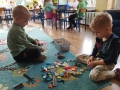  dzieci malują, bawią się, siedzą na dywanie i odnawiają temat z nauczycielem prowadzącym