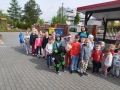 dzieci uczestniczące w ćwiczeniach ewakuacyjnych.W tle znajduje się czerwony wóz strażacki