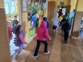 dzieci i opiekunka biegną po korytarzu przedszkolnym