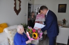 burmistrz wręcza Jubilatce dyplomy, w tle widać panią kierownik USC i członków rodziny