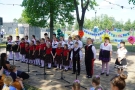 grupa dzieci w strojach estradowych występuje w plenerze. W tle widać napis: Podsumowanie roku artystycznego.