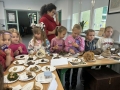 Dzieci i nauczycielka oglądają małe okazy przez lupę.