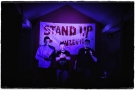 trzej mężczyźzni. W tle widać baner STAND UP