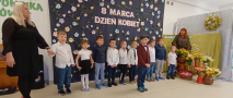 dzieci stoją przed dekoracją z okazji Dnia Kobiet