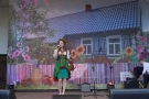 dziewczyna w stroju ludowym. W tle baer na którym widnieje drewniana chata